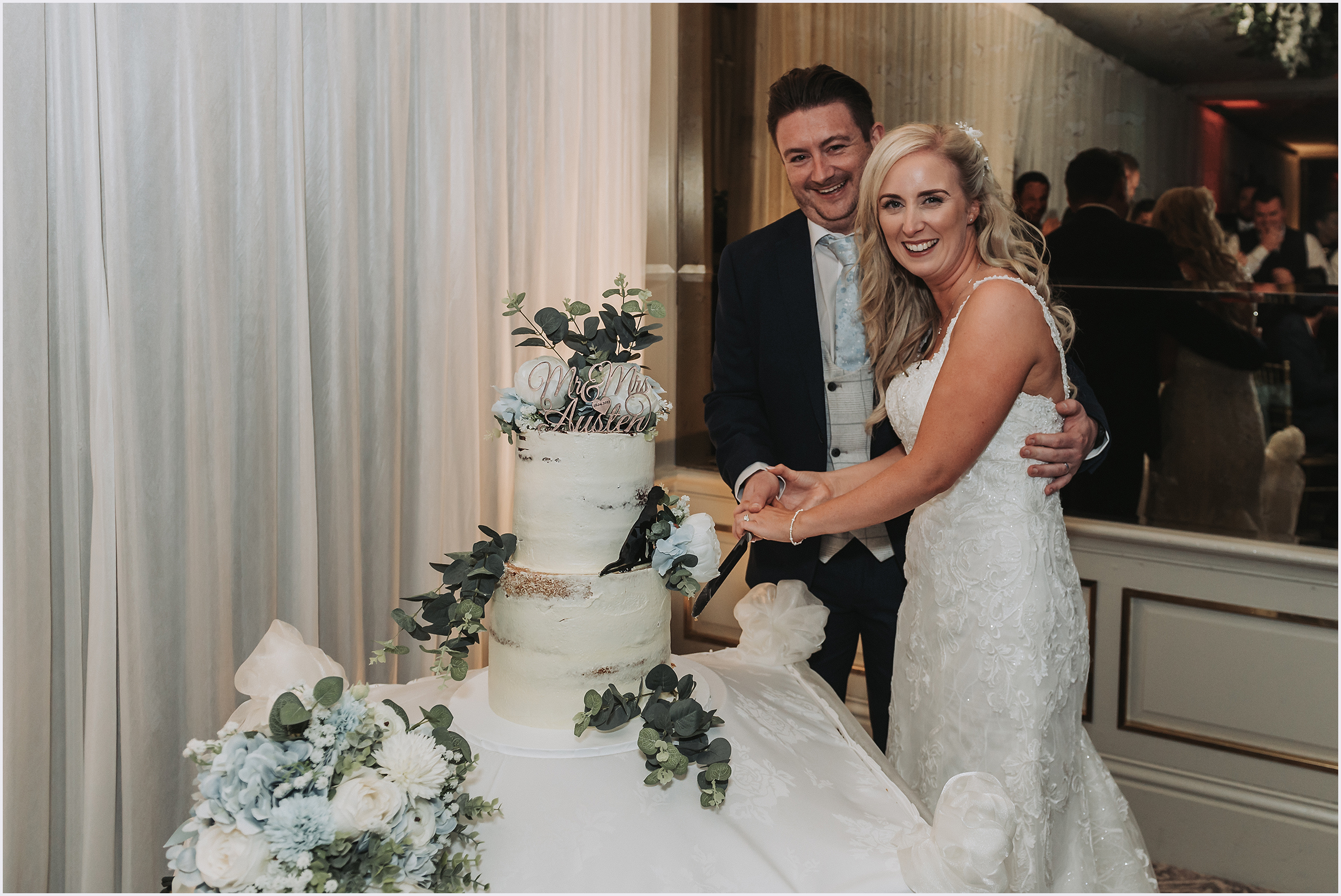 A newly married couple smiling at the camera as they cut their wedding cake during the evening reception at The Grosvenor Pulford Hotel and Spa.