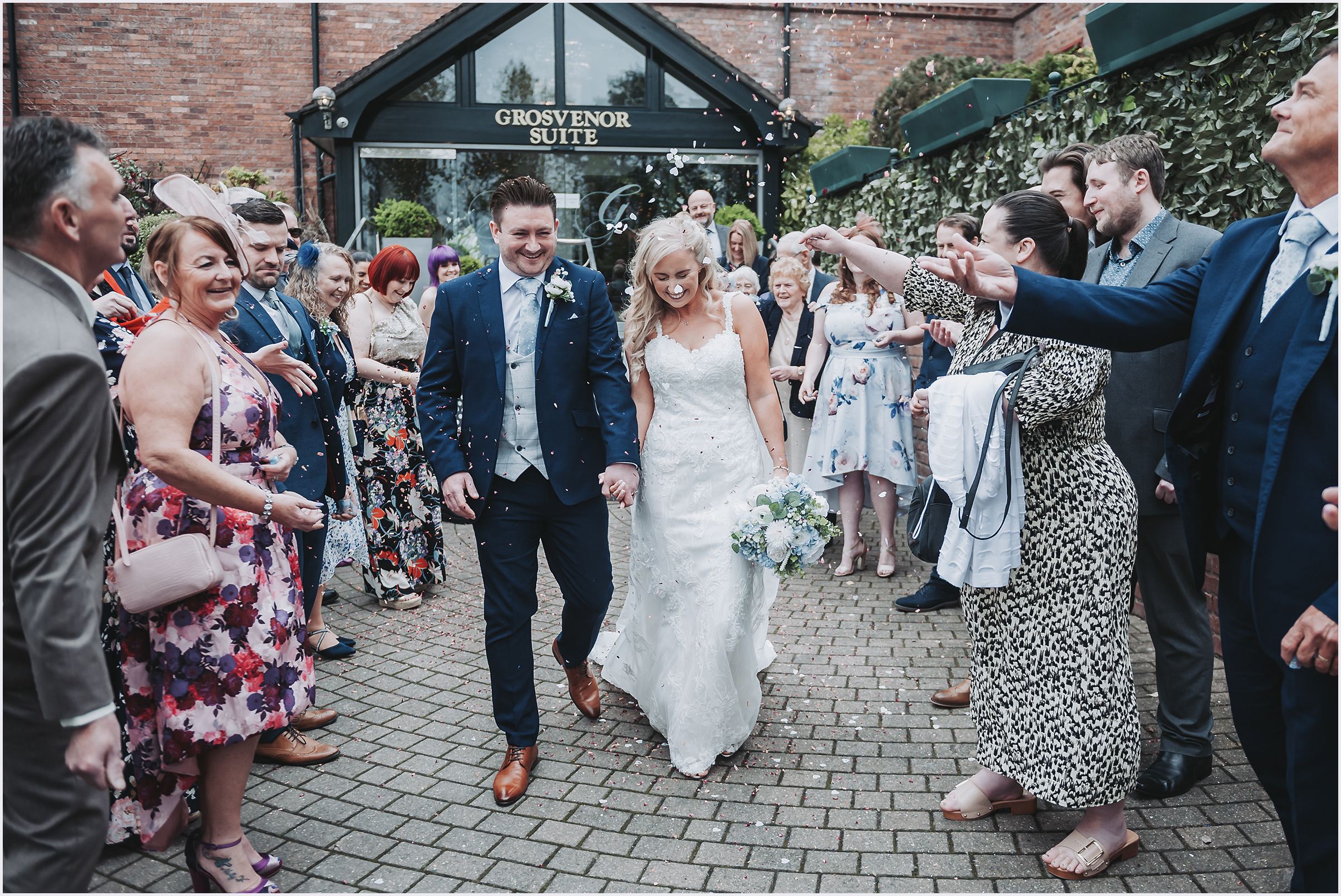 Guests throwing confetti at a newly married couple outside The Grosvenor Pulford Hotel and Spa.