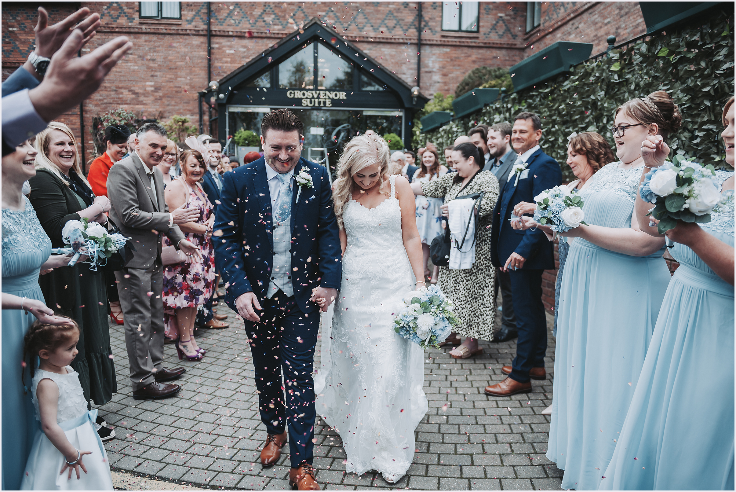 A newly married couple beam with happiness as their guests throw confetti at the after their wedding ceremony at The Grosvenor Pulford Hotel and Spa.