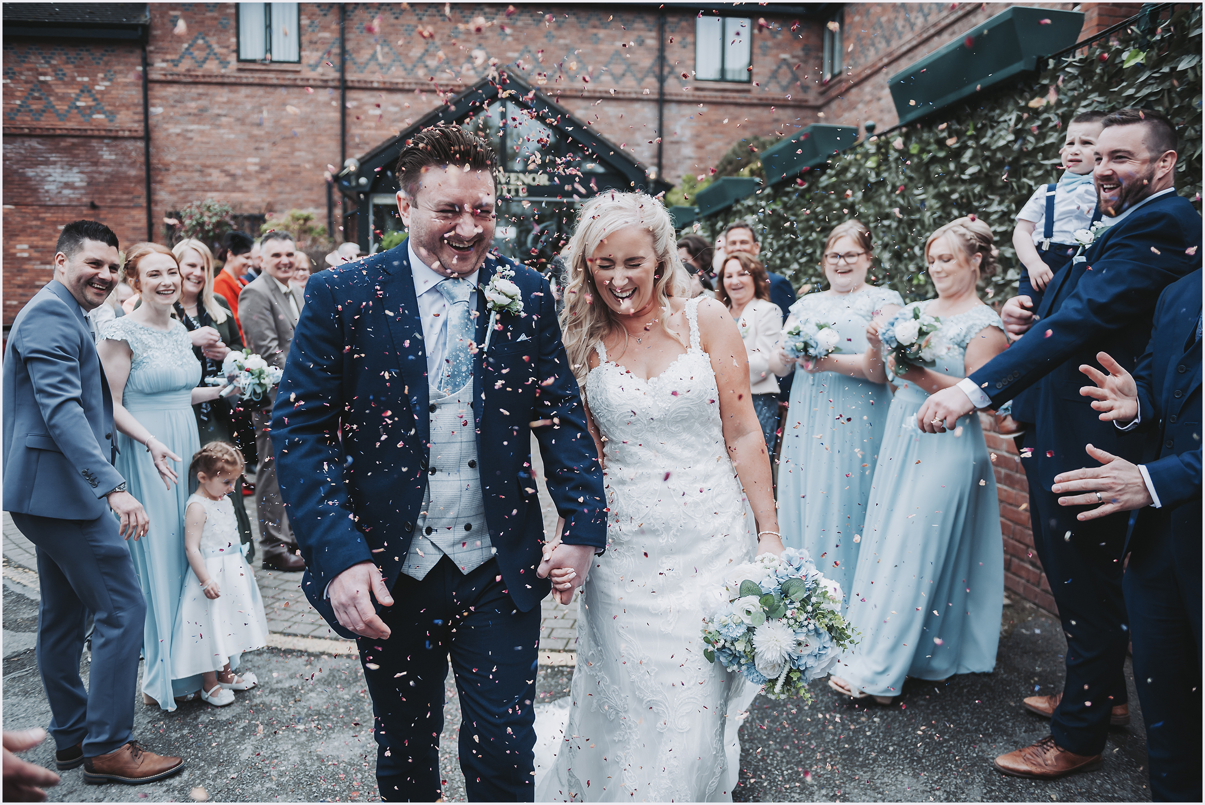 A newly married couple are showered with confetti by their guests after getting married.  Image captured by Cheshire wedding Photogapher Helena Jayne Photographer.