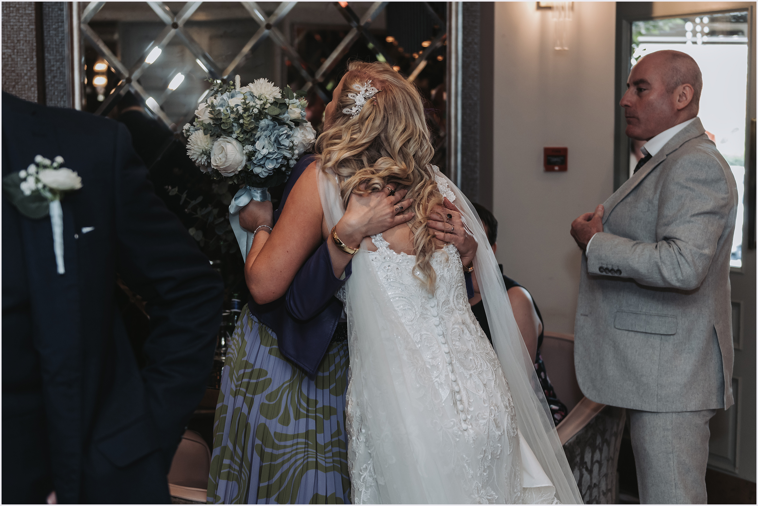 A bride is congratulated for getting married with an embrace with one her guests.  Image captured by North Wales Wedding Photographer Helena Jayne Photography.