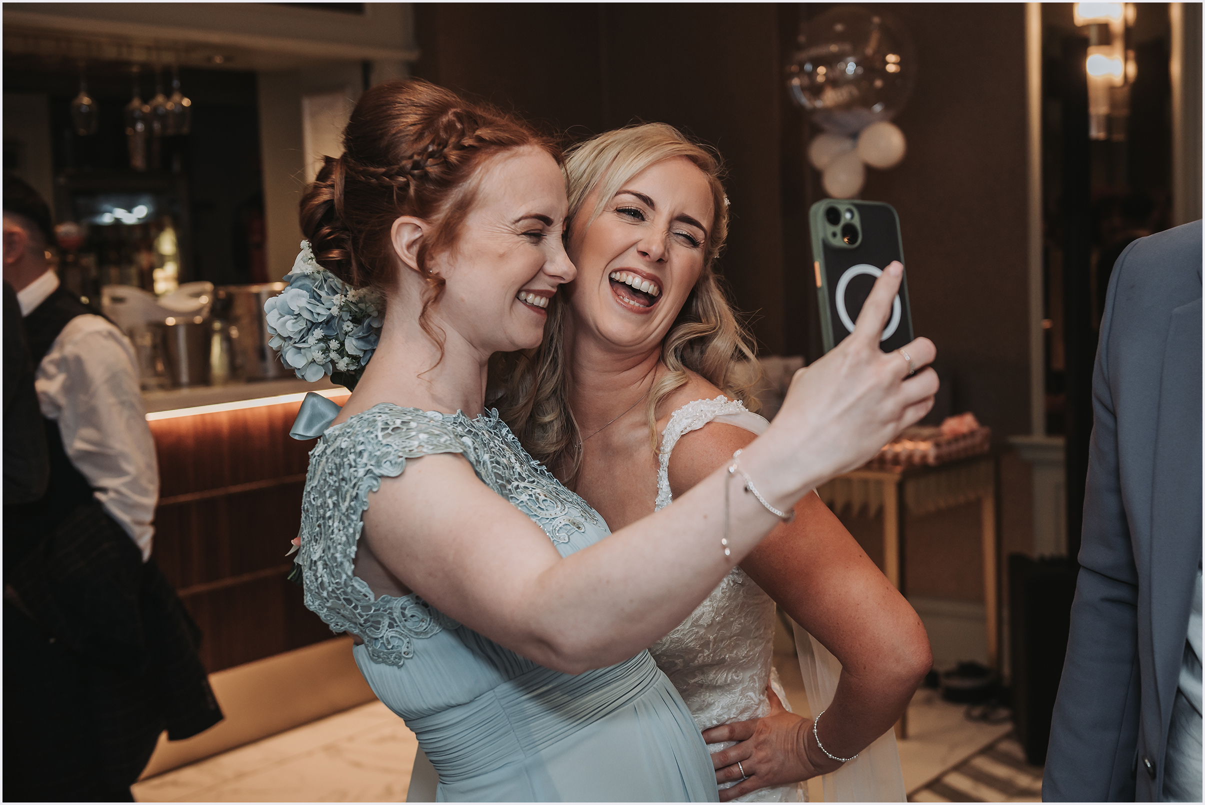 A bride and her bridesmaid pulling faces while taking a selfie during the drinks reception at a wedding at The Grosveor Pulford Hotel and Spa.