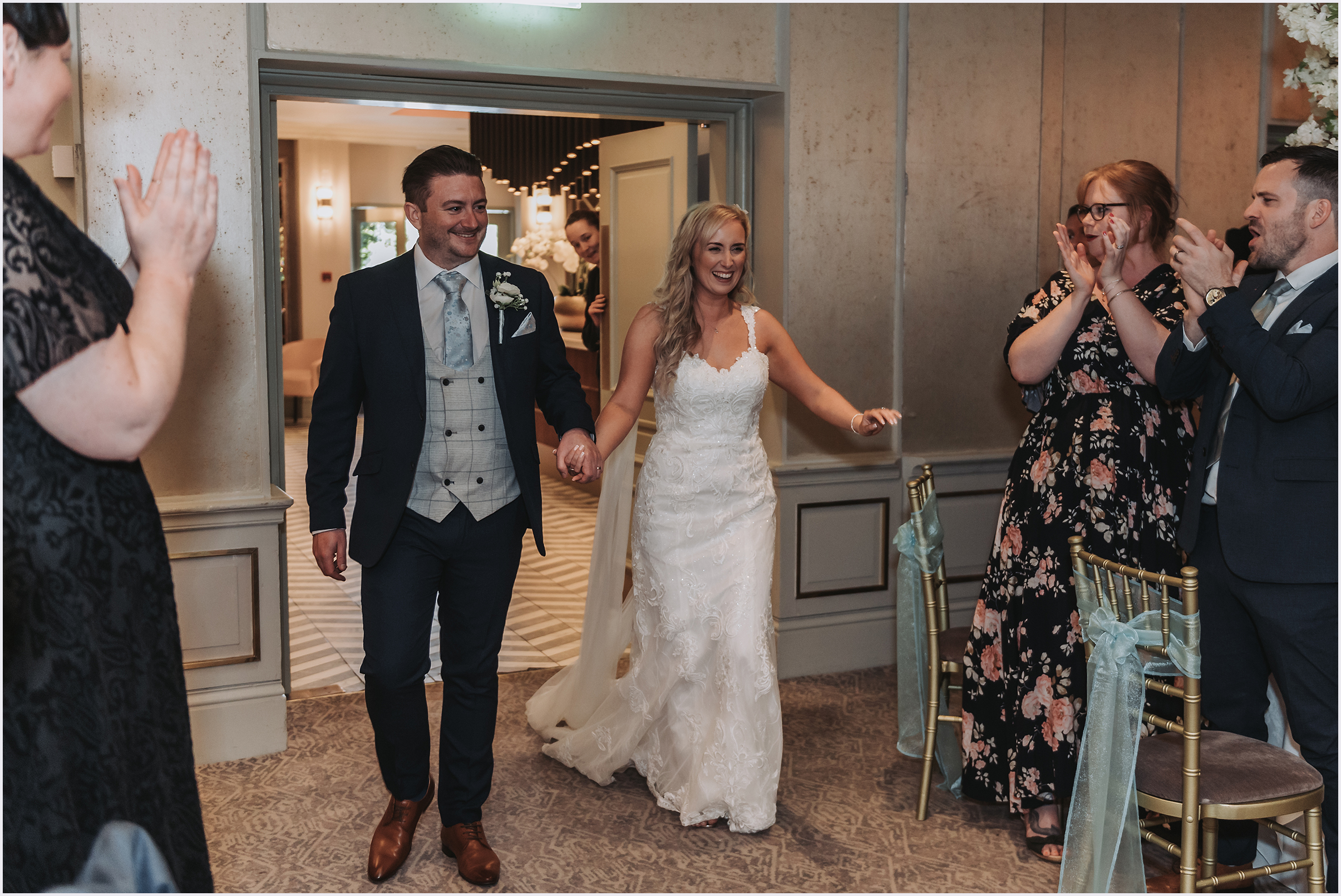 Guests standing and applauding a bride and groom as they enter the room for the wedding breakfast at The Grosvenor Pulford Hotel and Spa.