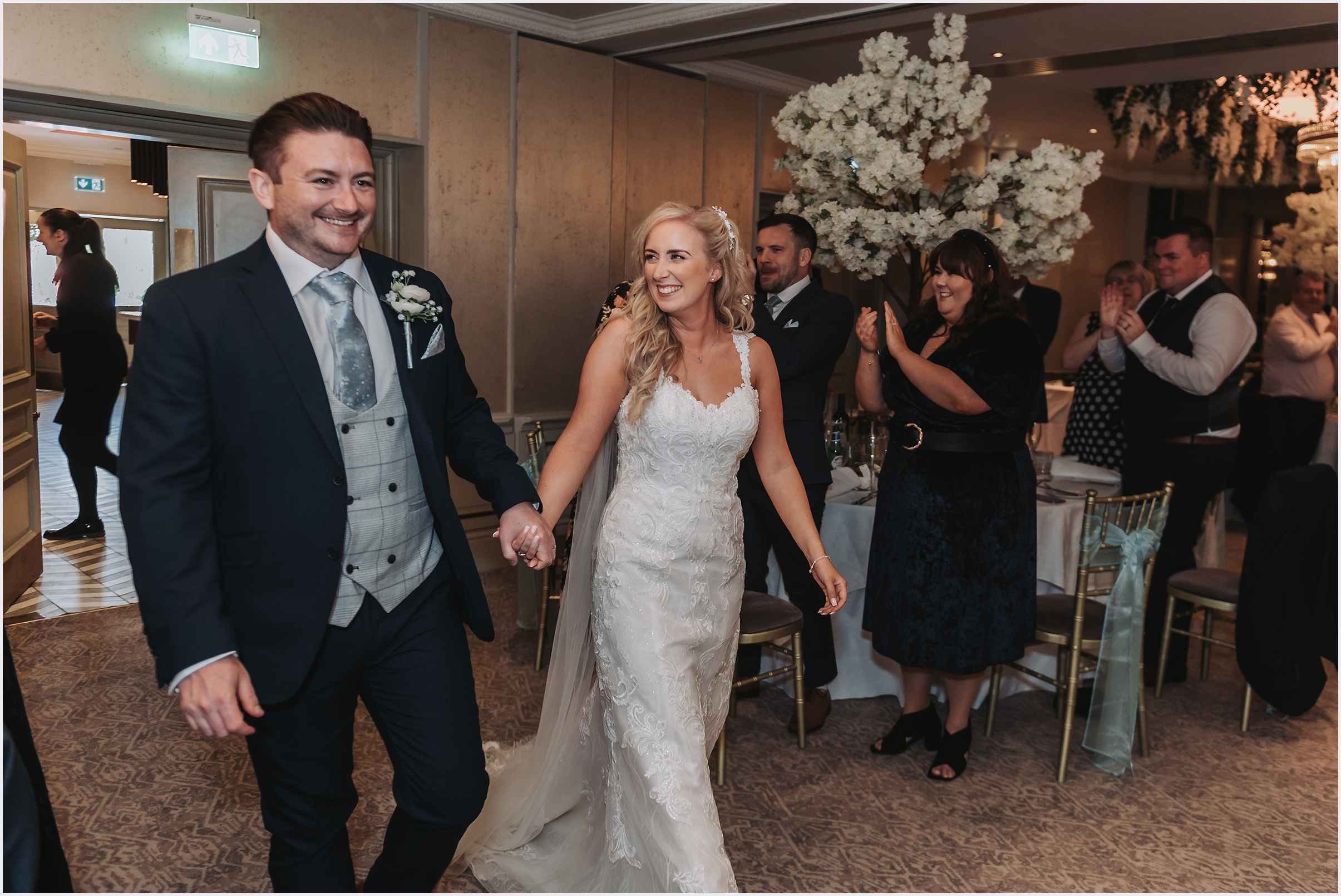 A bride and groom walking hand in hand smiling at each other as they enter the room where their wedding breakfast will be served at The Grosvebor Pulford Hotel and Spa.