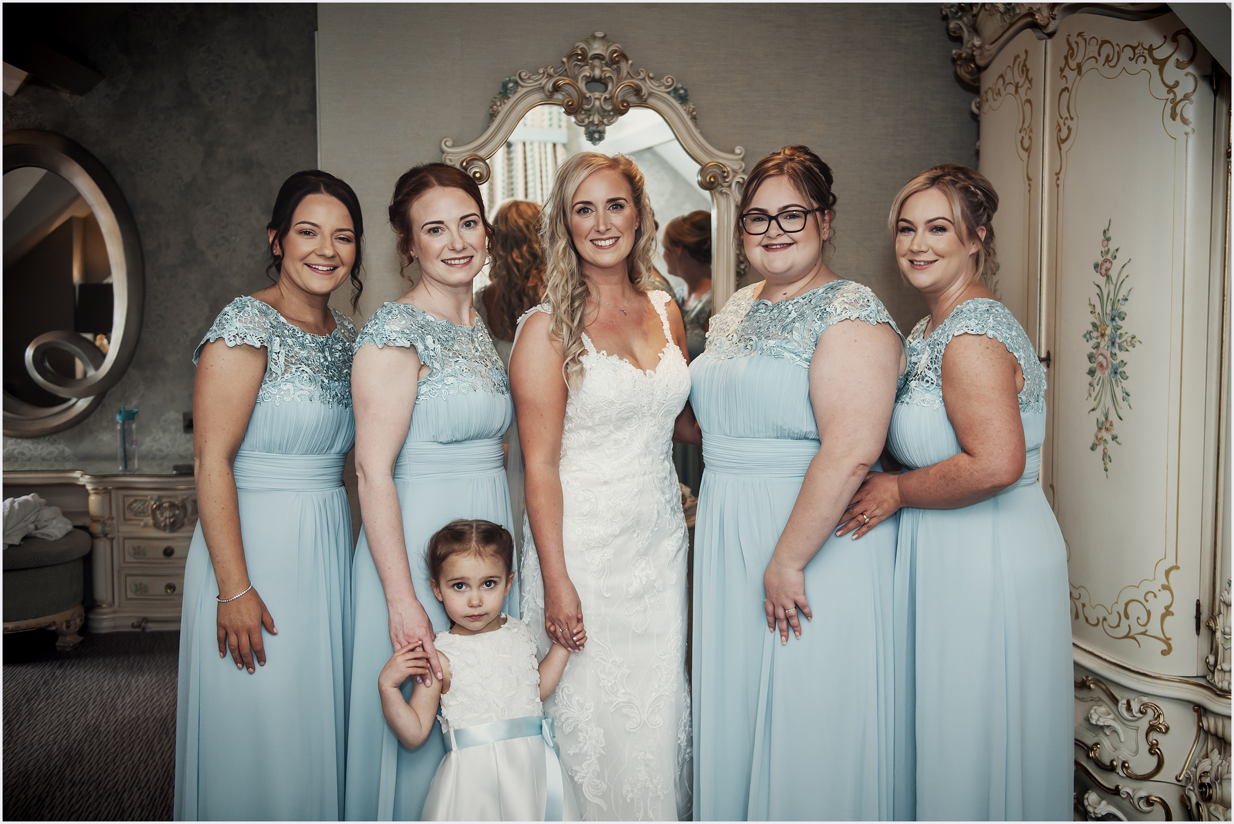 A bride poses with her four bridesmaids and flower girl before her wedding.