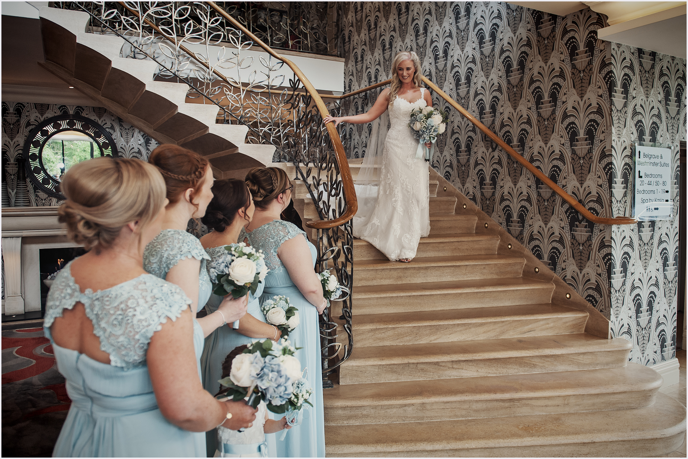 A bride walks down the beautiful staircase at The Grosvenor Pulford Hotel and Spa before her wedding ceremony.