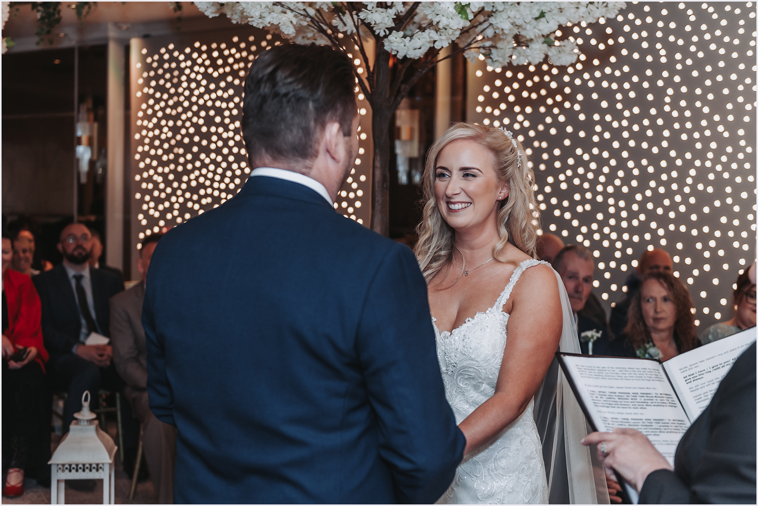 A bride smiling and her groom as they exchange vows during their wedding ceremony.  Image captured by Cheshire wedding Photographer Helena Jayne Photographer.