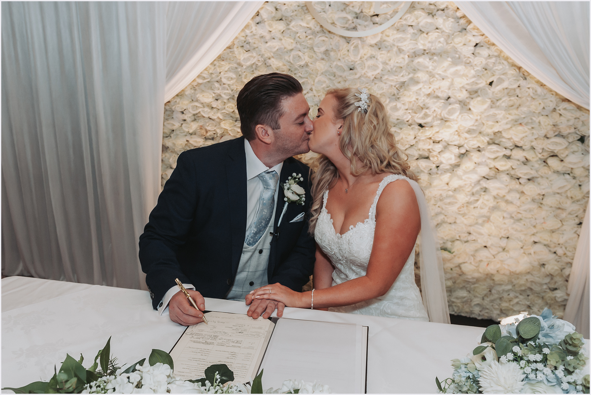 A bride and groom kissing after signing the register at their wedding.