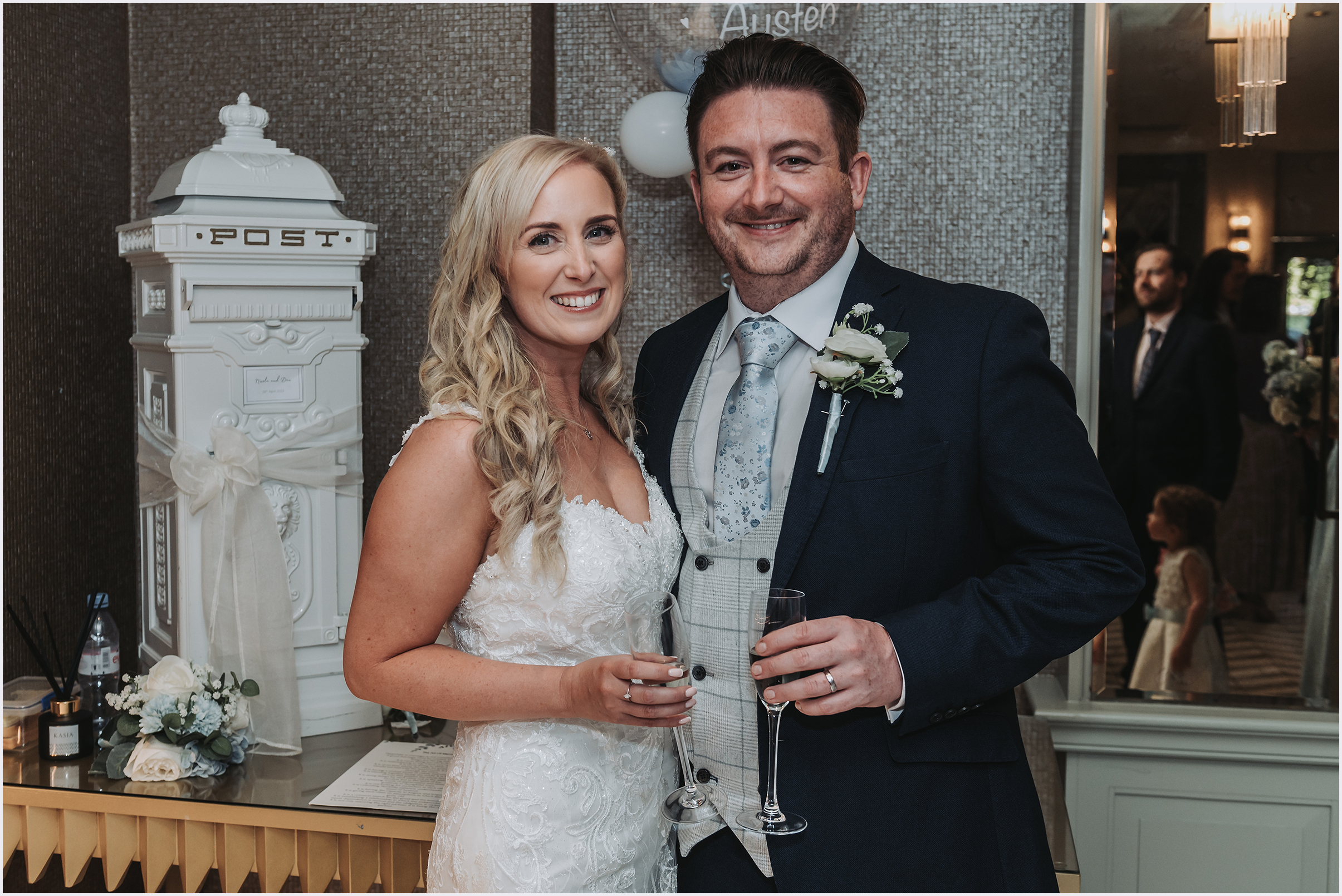 A newly married couple standing close together smiling at the camera during the drinks reception at their wedding.  Image captured by north Wales Wedding Photographer Helena Jayne Photography.