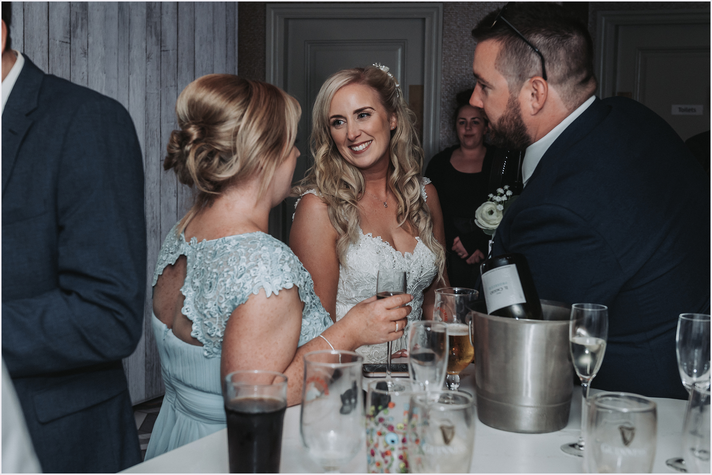 A bride smiling happily at one her bridesmaids as they chat at the drinks reception at The Grosvenor Pulford Hotel and Spa