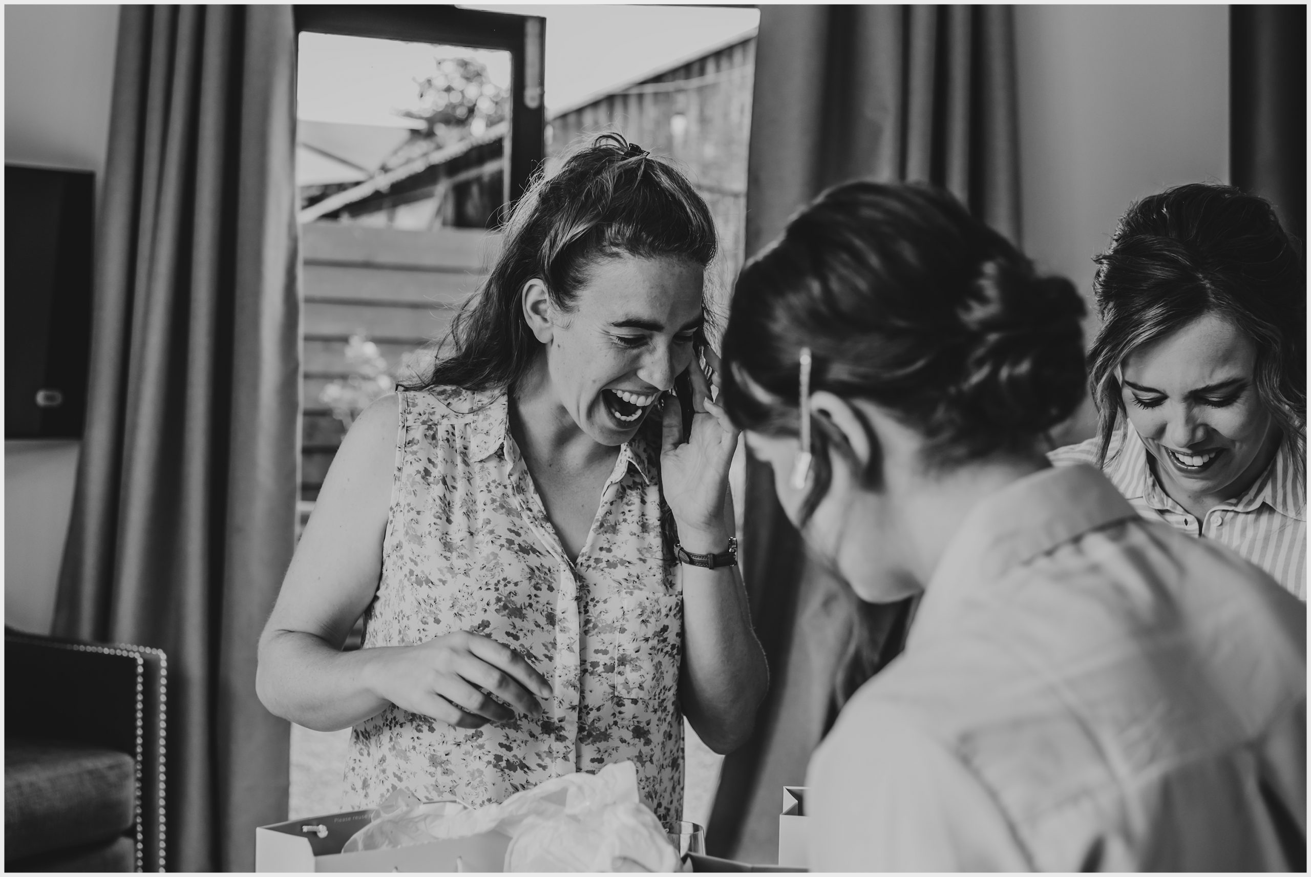 An excited bridesmaid opens gifts with her best friends during the morning preparations of her best friend's wedding.  Image captured by Helena Jayne Photography North Wales Wedding Photographer