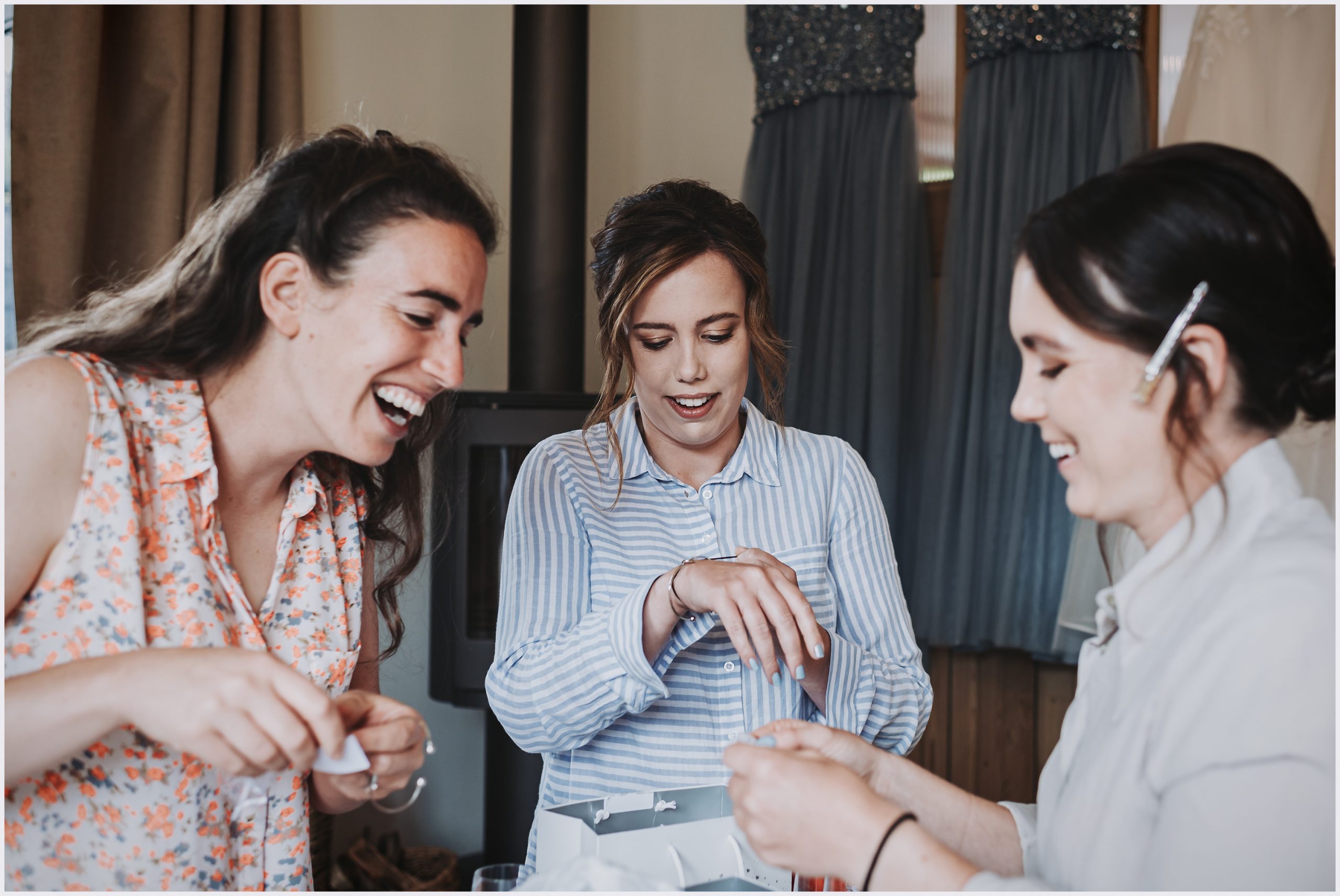 A Group of bridesmaids excitedly open gifts from the bride on the morning of her wedding.  Image captured by North Wales wedding photographer Helena Jayne Photography