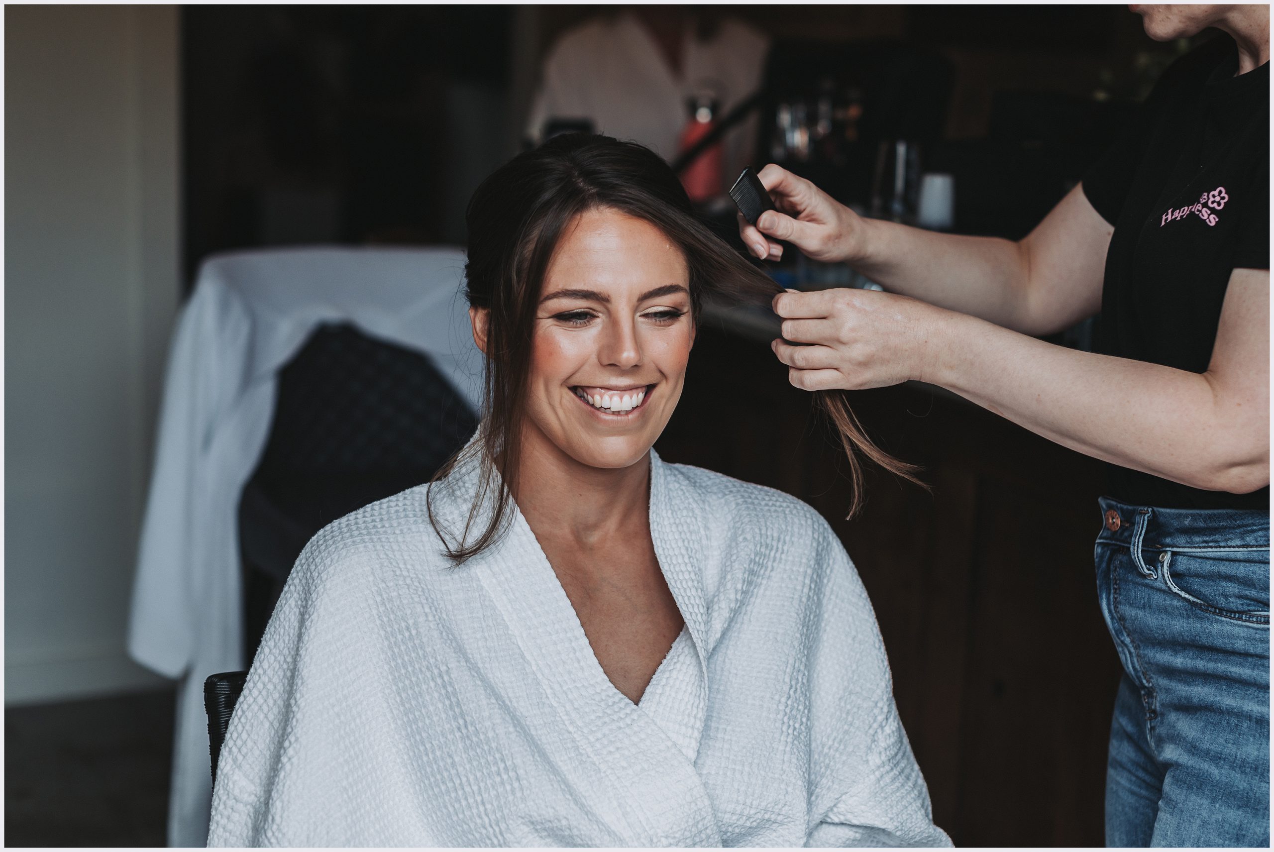 A beautiful bride wearing a white bath robe getting her hair done on the morning of her wedding.  Image captured by Helena Jayne Photography Cheshire wedding photographer