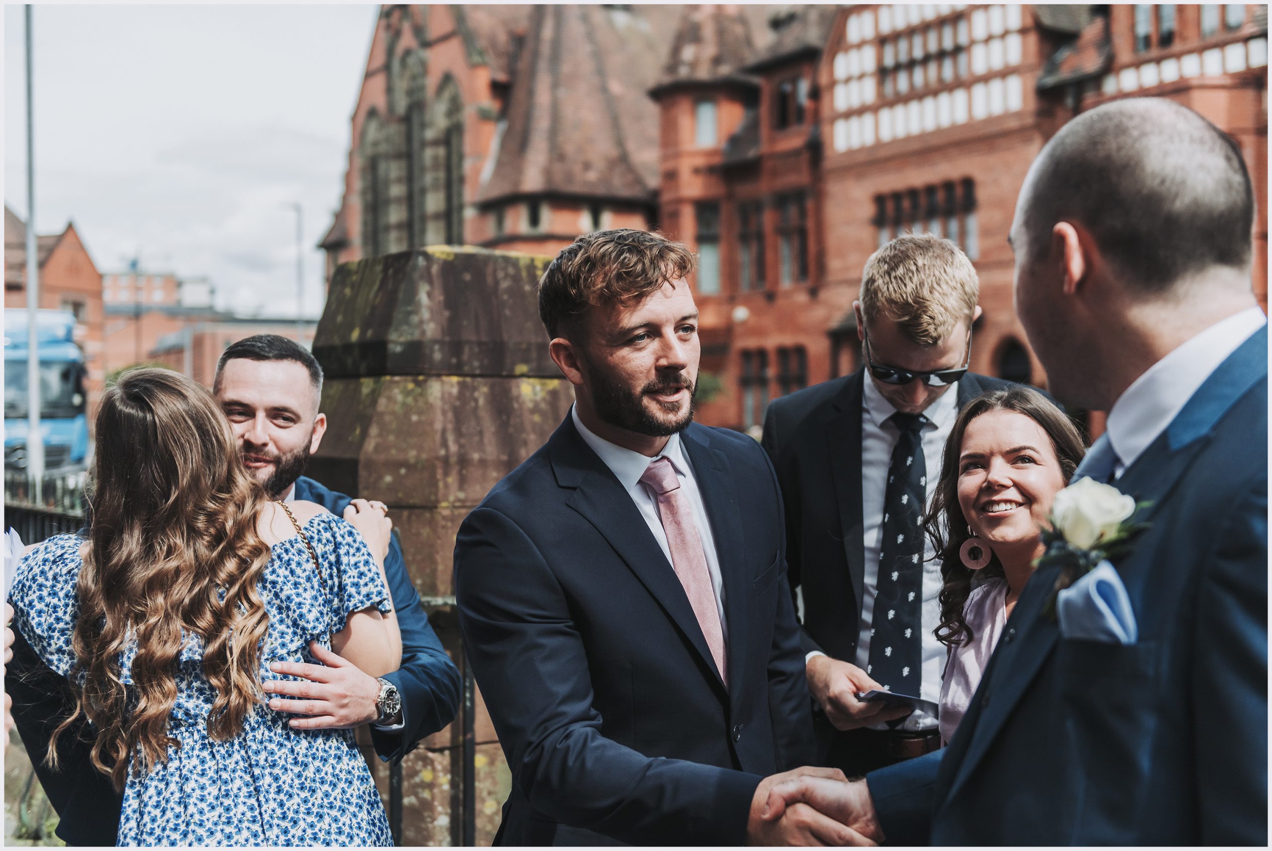 A wedding guest shakes the hand of one of the ushers outside the church where is about to get married.  Image captured by Helena Jayne Photography Chester wedding photographer