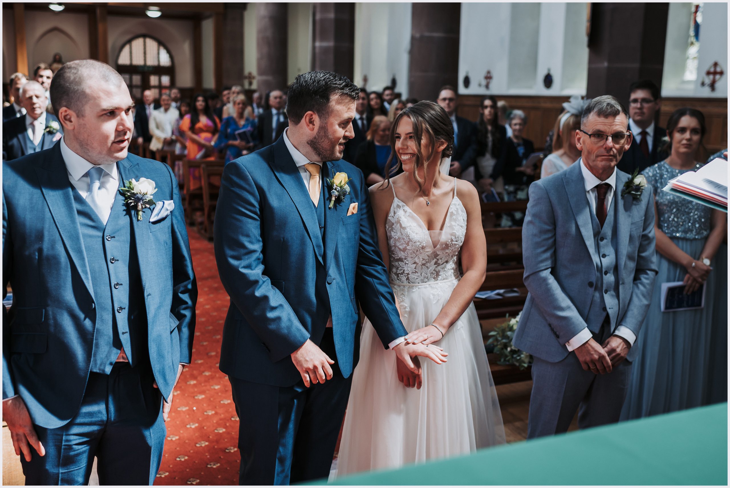 A bride and groom smile and look into each other's eyes during their church wedding ceremony.  Image captured by wedding photographer Helena Jayne Photography