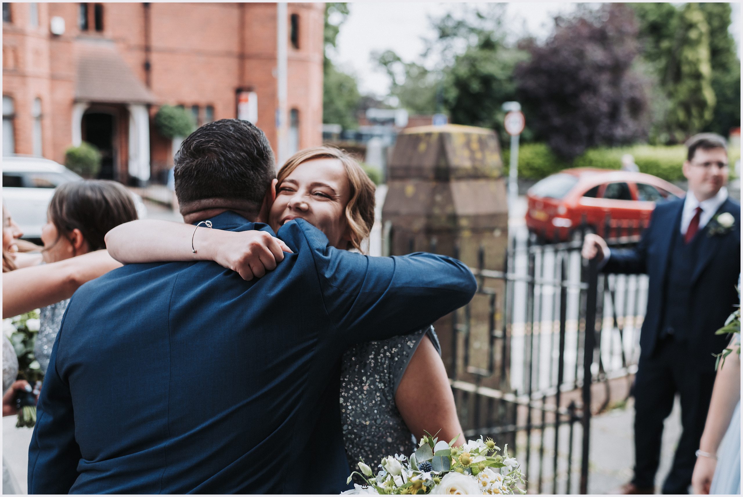 A bridesmaid hugs the groom congratulating him after their church wedding ceremony.  Image captured by North Wales wedding photographer Helena Jayne Photography