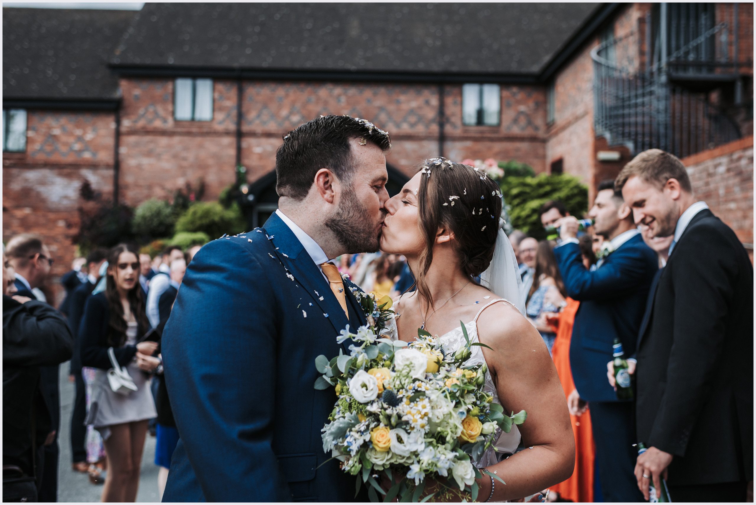 A bride and groom share a kiss covered in confetti at The Grosvenor Pulford Hotel and Spa