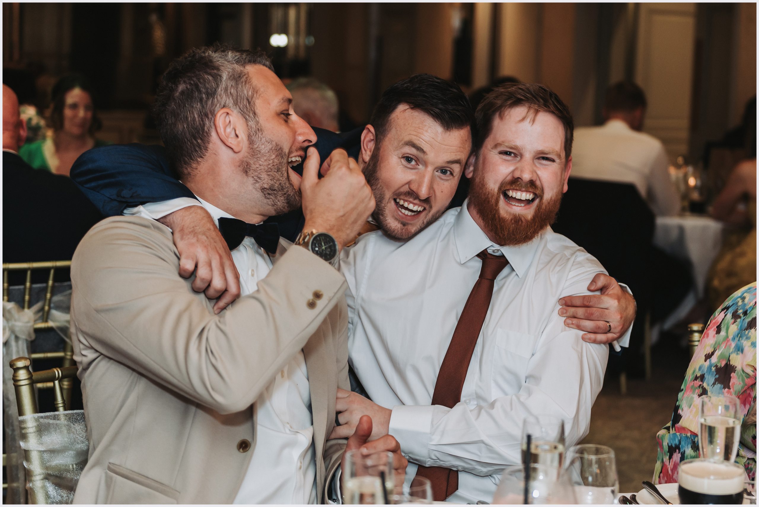 The groom hugs two friends as they laugh and joke in The Grosvenor Suite of the The Grosvenor Pulford Hotel and Spa