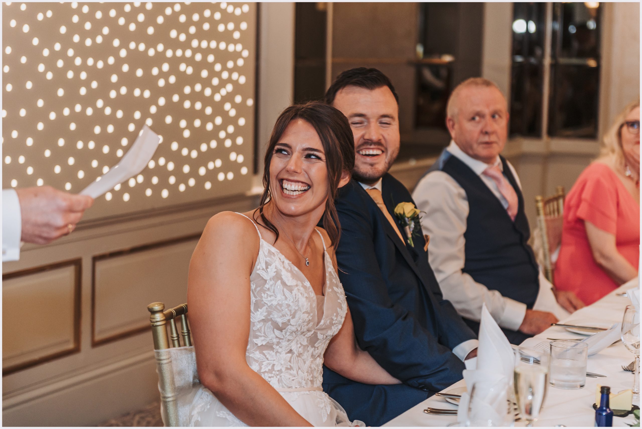 A bride laughs during her father's speech at her wedding at The Grosvenor Pulford Hotel and Spa.  Image captured by Helena Jayne Photography a wedding photographer based in Chester