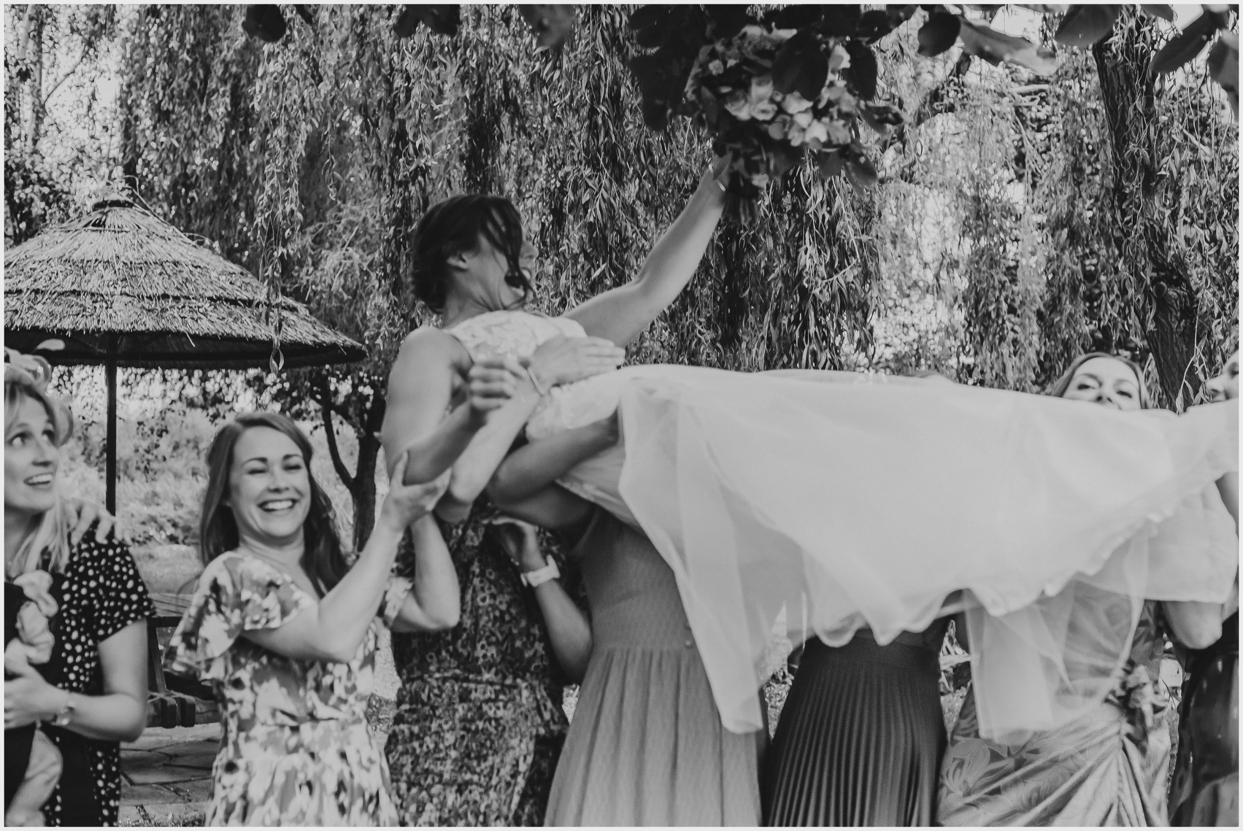 A laughing bride is thrown into the air by all of her friends at The Grosvenor Pulford Hotel and Spa