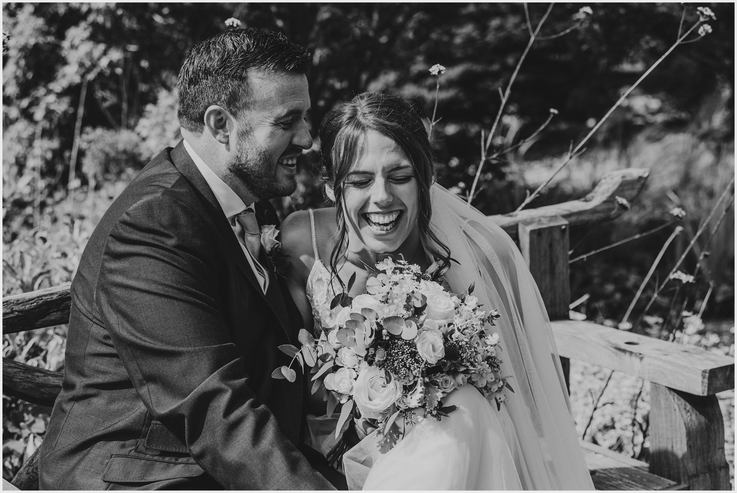 A bride bursts into laughter while sitting on a rustic bench in the Asian Gardens at The Grosvenor Pulford Hotel and Spa.  Image captured by Helena Jayne Photography a preferred supplier of the Grosvenor Pulford Hotel and Spa