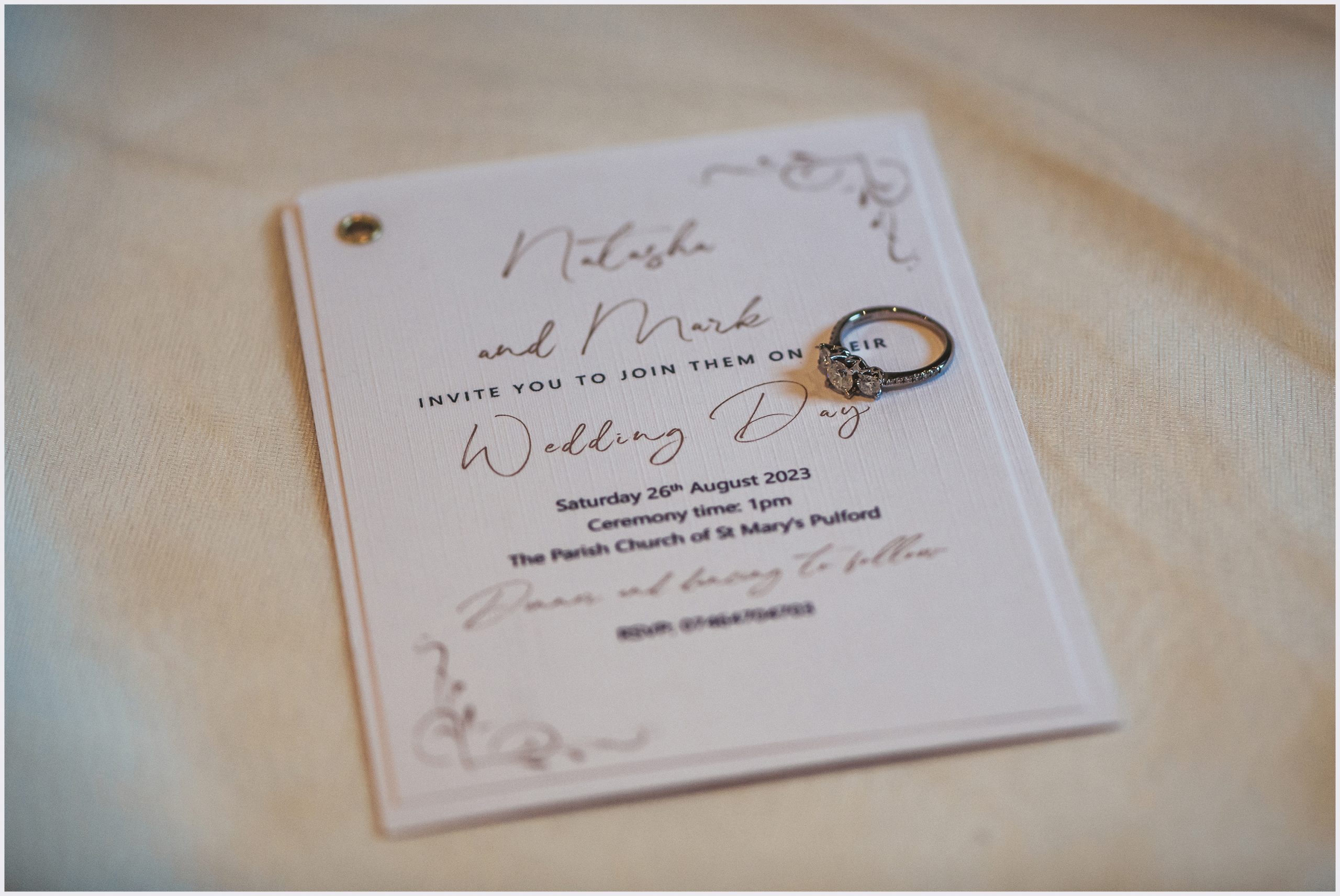 A beautiful engagement ring resting on a wedding invitation.