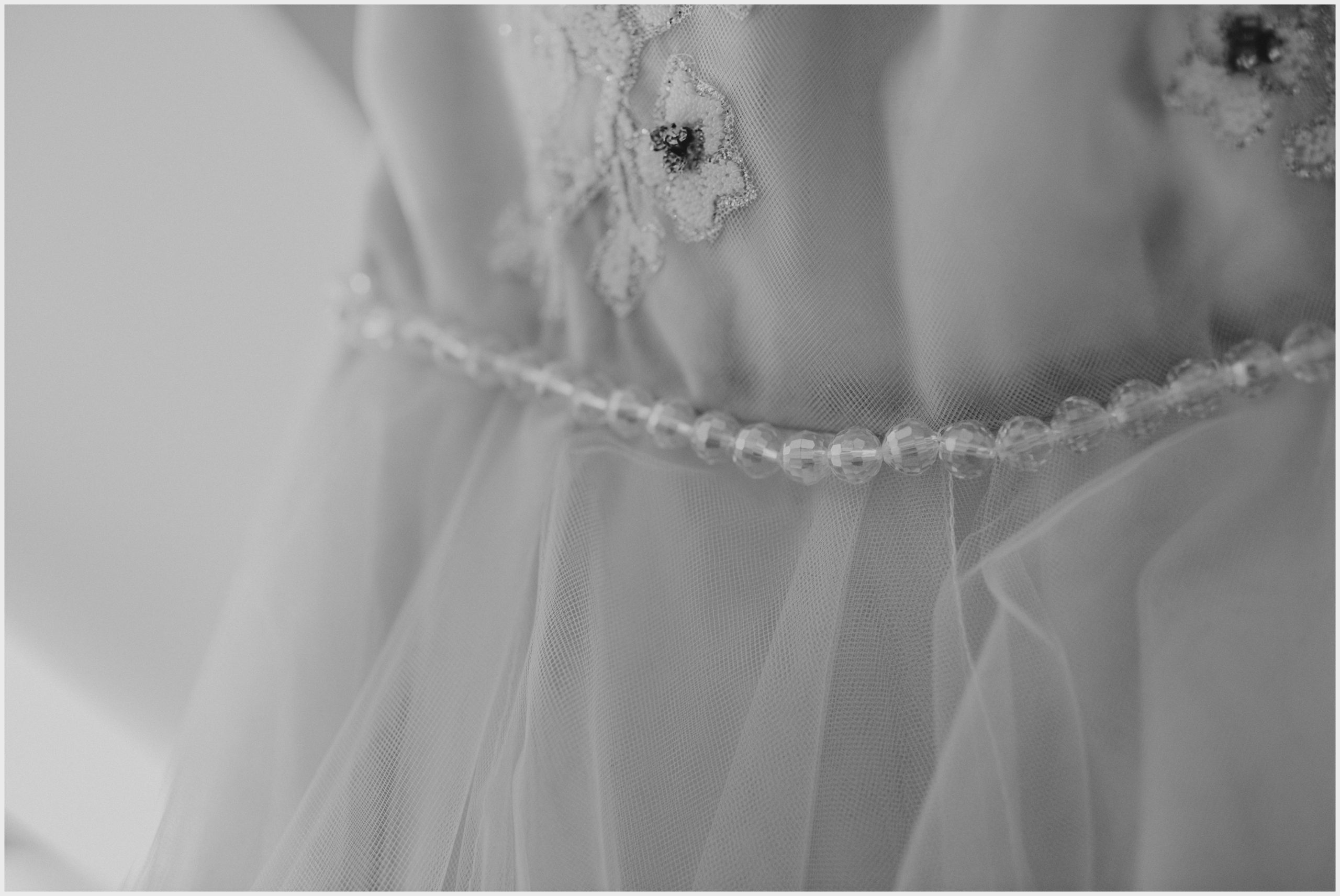 The waist band beaded belt of a beautiful wedding dress. Image captured by Helena Jayne Photography, Cheshire wedding photographer