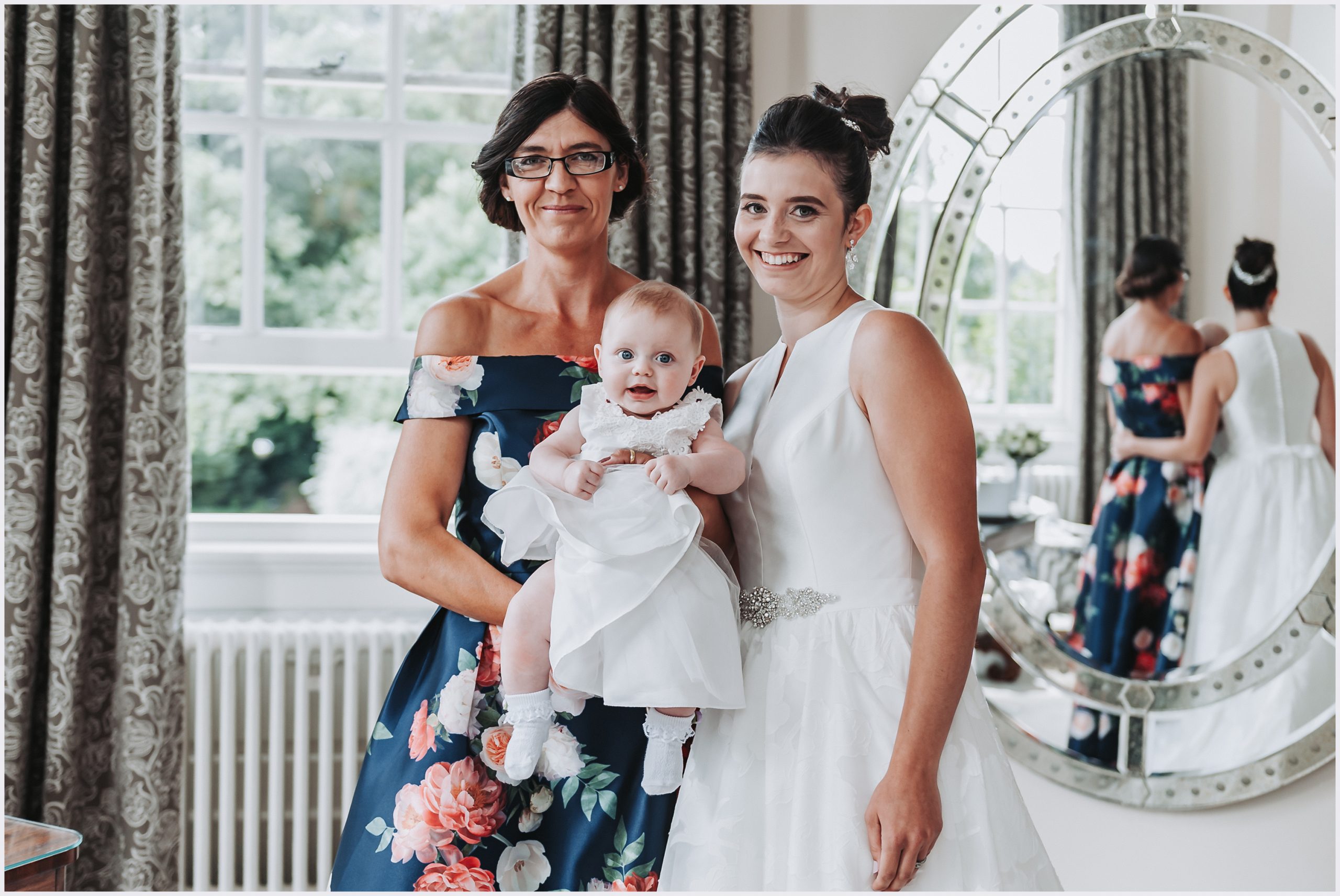 A bride, her daughter and her mother pose for a photograph in the beautiful bridal suite at Iscoyd Park on the morning of her wedding.  Image captured by Welsh wedding Photographer Helena Jayne Photography.