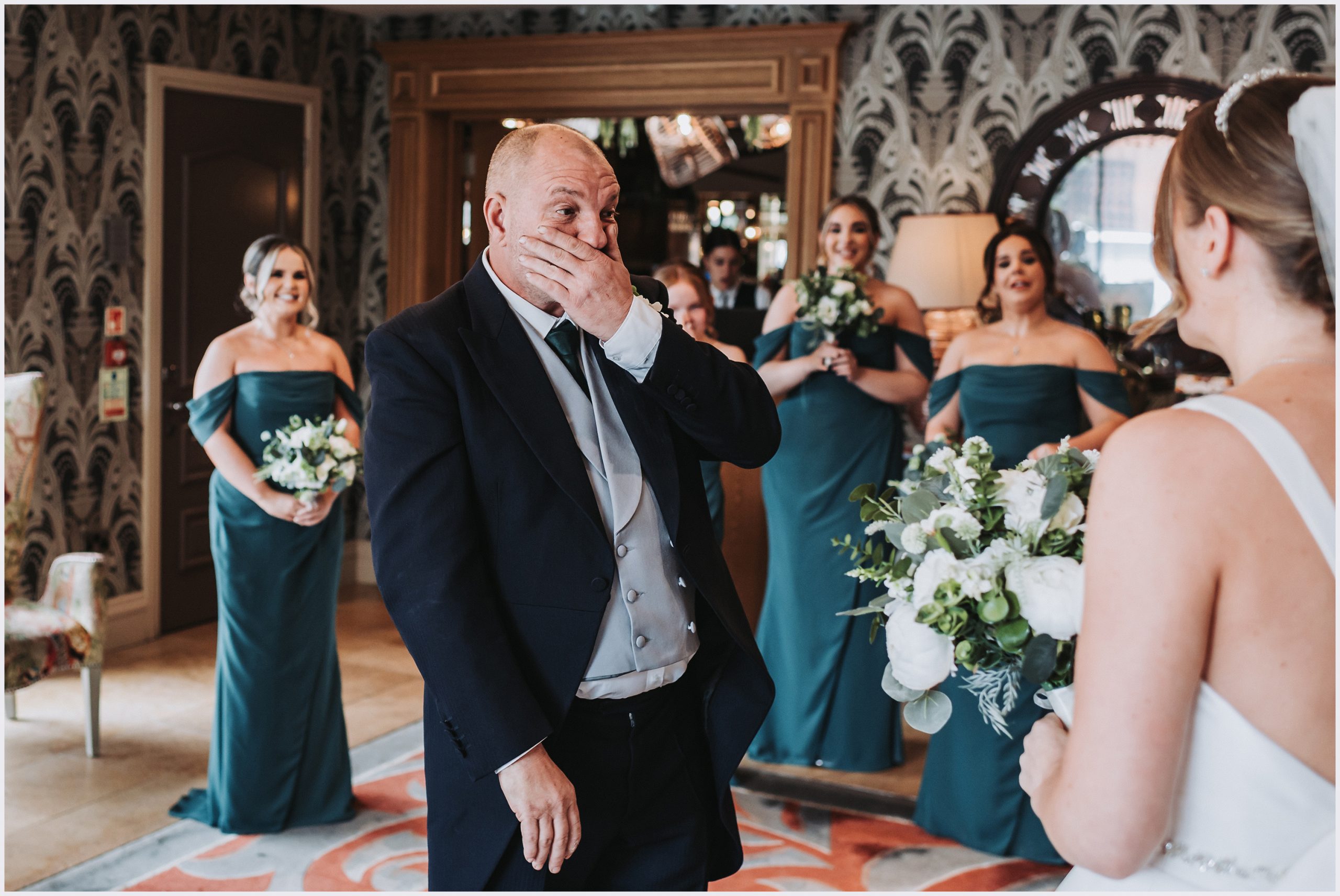 An emotional father of the bride looks at his daughter for the first time in her wedding dress.  Bridesmaids are standing in the background smiling.  Image captured at The Grosvenor Pulford Hotel and Spa by Helena Jayne photography a wedding photographer