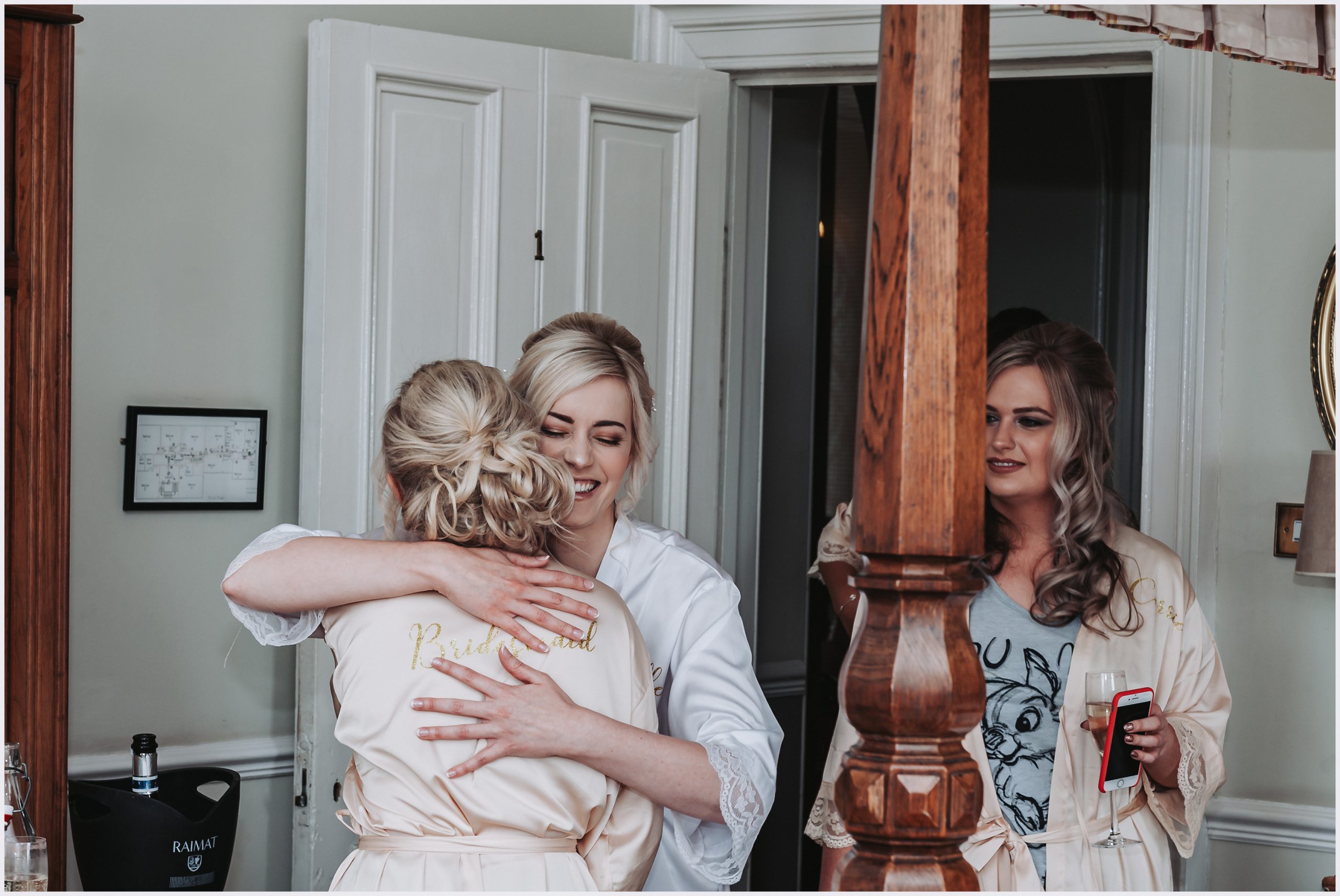 A beautiful bride hugs one of her bridesmaids in the gorgeous bridal suite at Willington Hall Hotel on the morning of the wedding