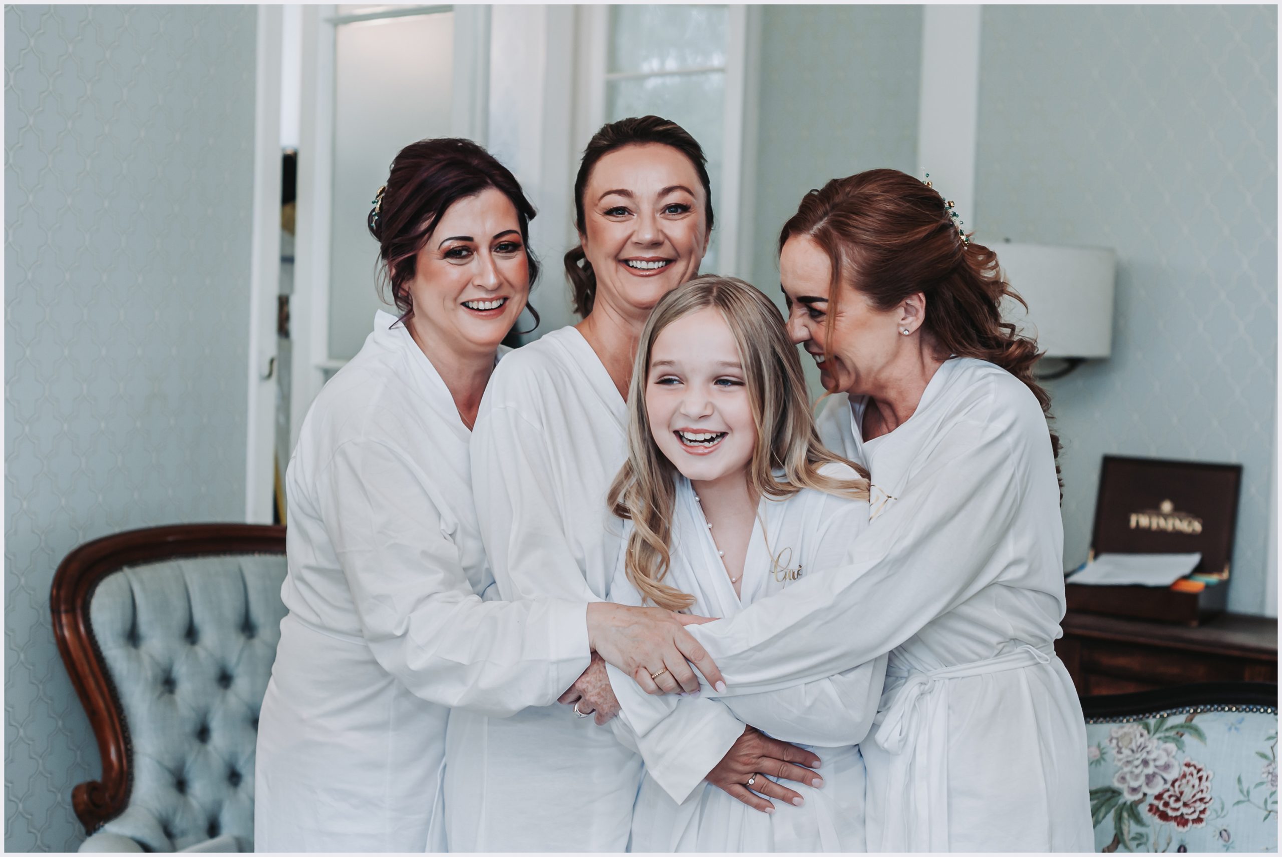 A bride and her two bridesmaids and flower girl pose for a candid shot in the beautiful dressing room at Soughton Hall.  Image captured by north Wales based photographer helena Jayne Photography.