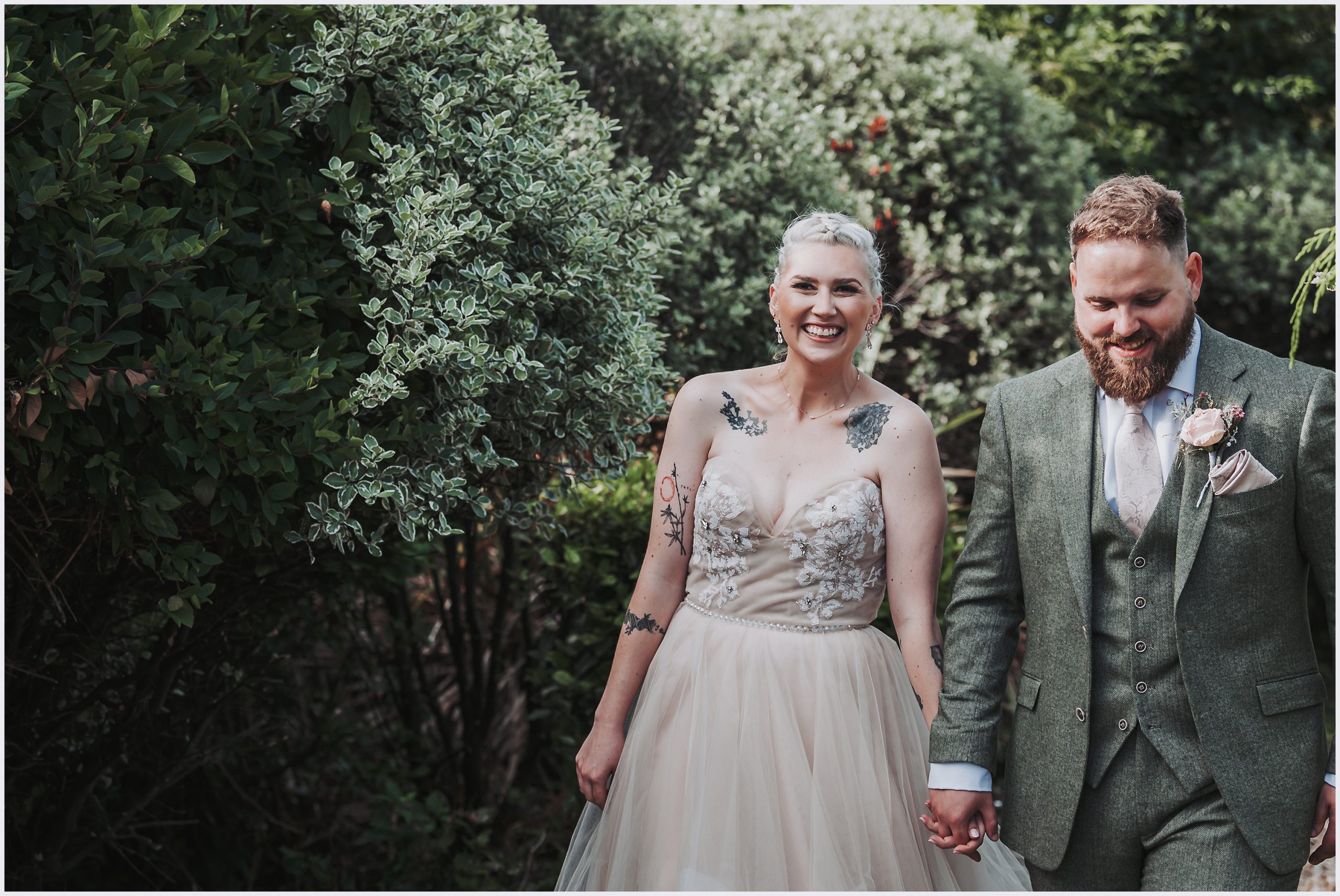 Cheshire's Fairytale Wedding: Bride and Groom in a Storybook Setting.  A bride smiles happily at the camera she walks hand in hand with her husband at The Grosvenor Pulford Hotel and Spa