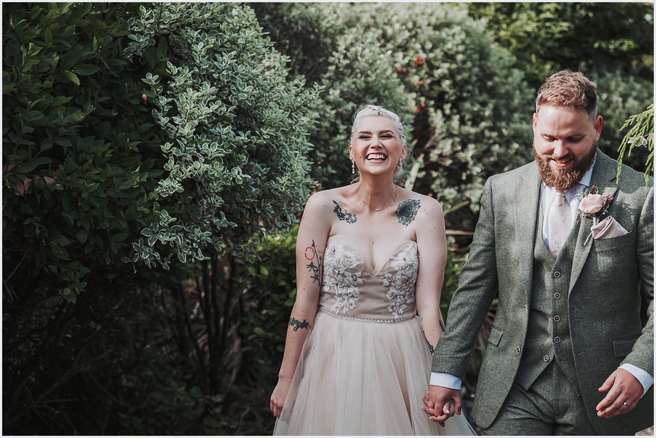 North Wales' Love Affair: Bride and Groom's Unforgettable Wedding Moment. A bride laughs and looks so happy as she walks along hand in hand with her husband at The Grosvenor Pulford Hotel and Spa