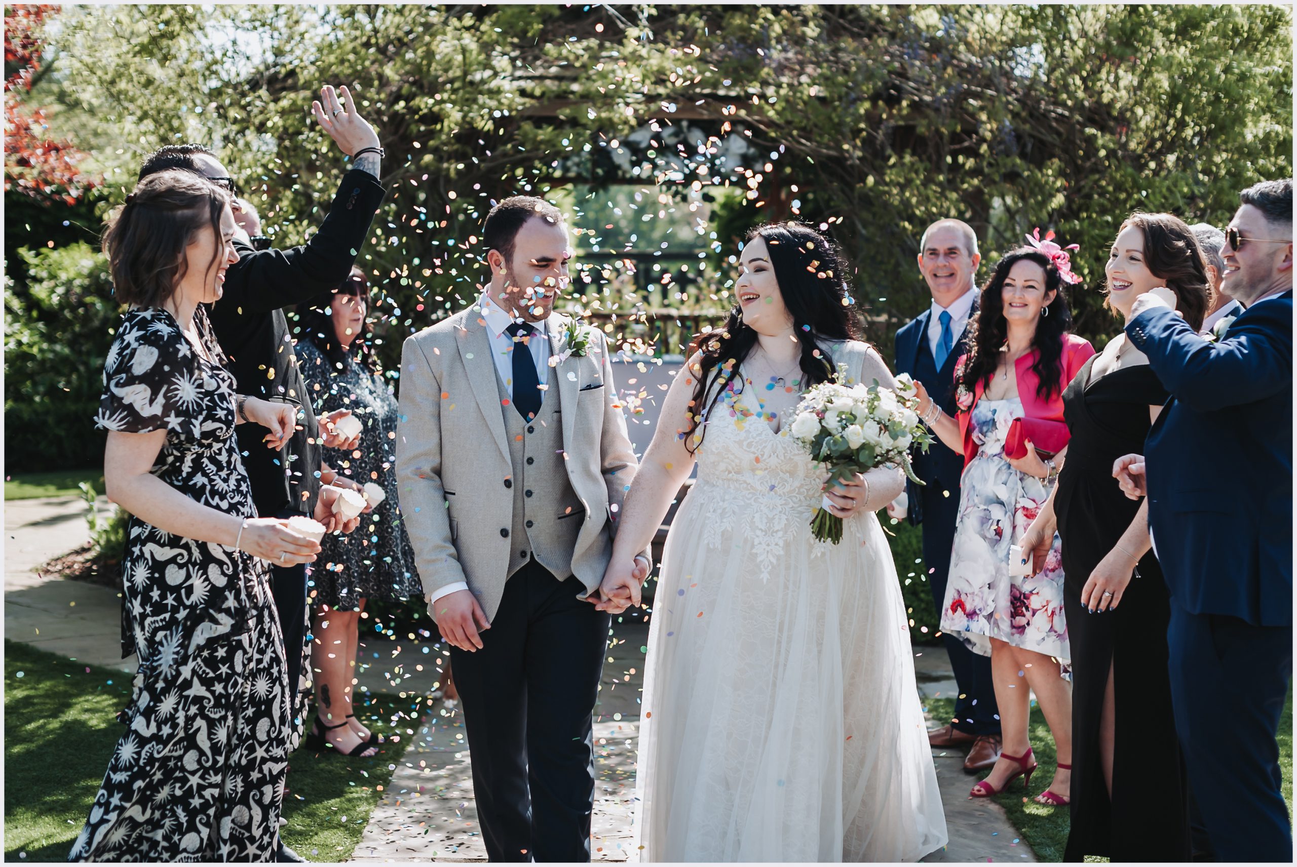 A beautiful bride and her groom smile and laugh as guests throw confetti over them at Pryors Hayes Golf Clun in Cheshire.  Image captured by Cheshire Wedding Photographer Helena Jayne Photography